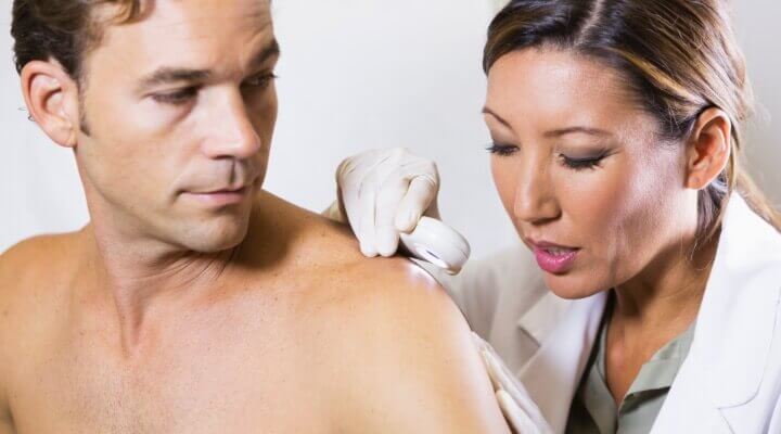 Doctor examining skin on a man's shoulder